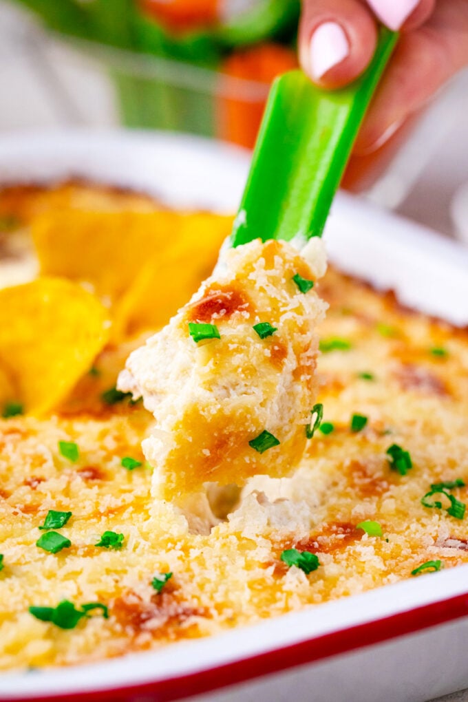 Dipping a celery stick in cheesy chicken Caesar dip.