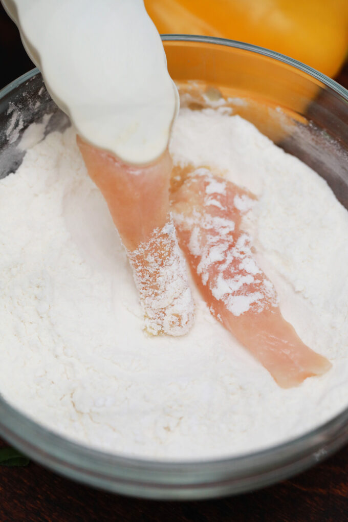 Coating chicken strips in flour and cornstarch.