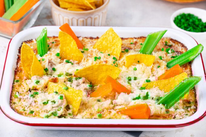 Homemade chicken Caesar dip with chips and veggies sticks.