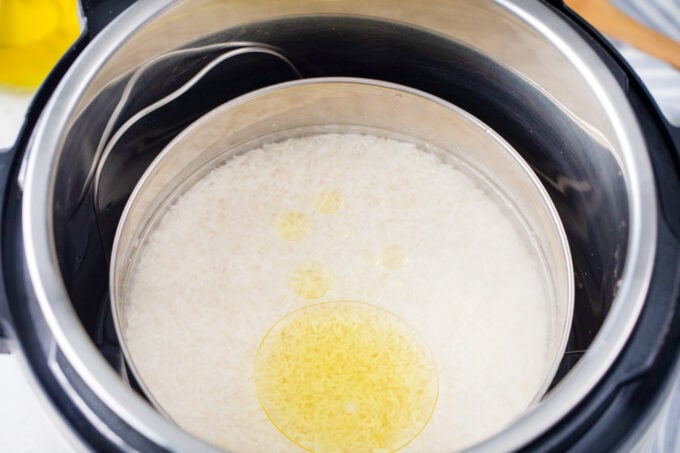 White rice in with water and oil in a stainless steel pan in the Instant Pot.