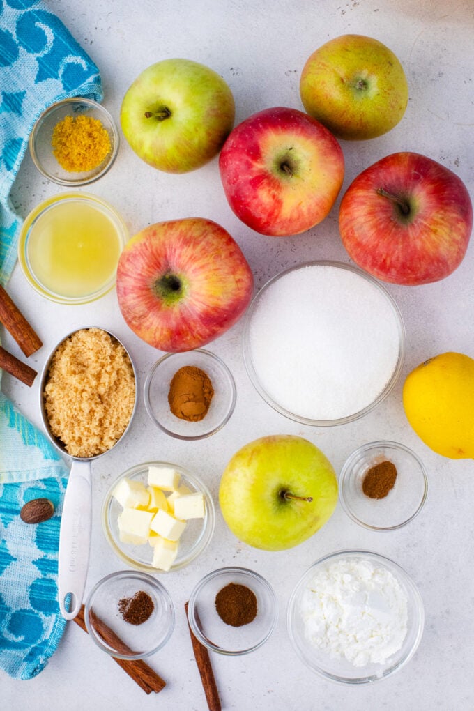 Overhead shot of apple pie filling ingredients arranged on a white surface.