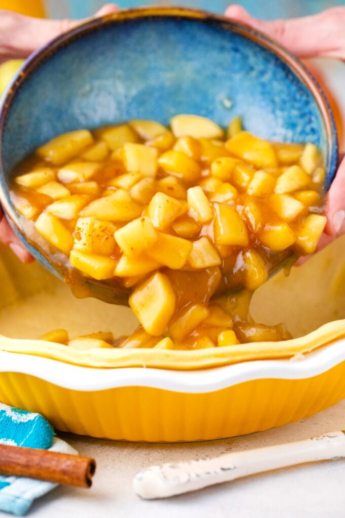 Pouring apple pie filling in a pie crust.