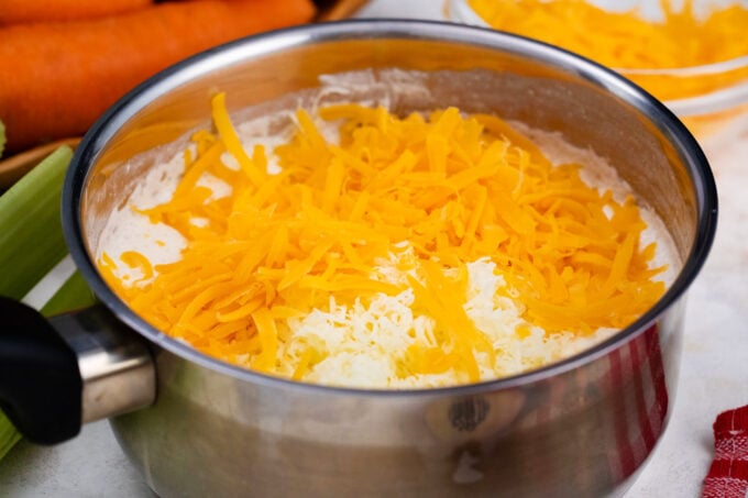 Stirring shredded cheese into beer cheese dip.