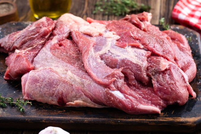 Season chuck roast on a cutting board.