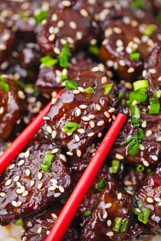 chopsticks holding a piece of crispy sticky honey garlic beef