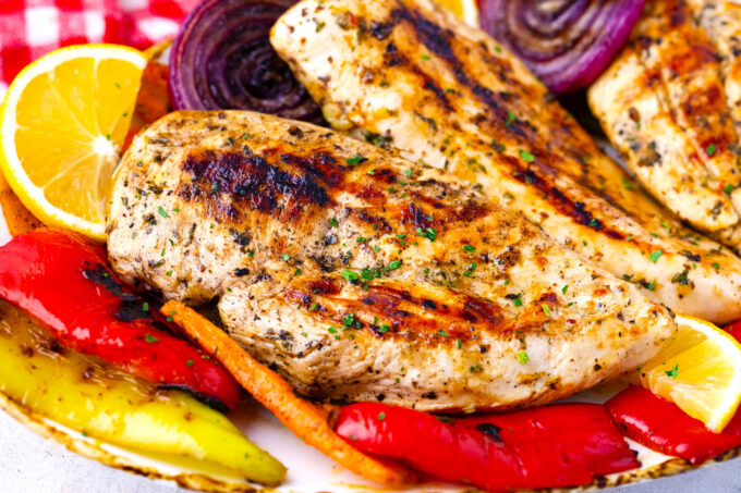 A plate of grilled chicken breasts and veggies.