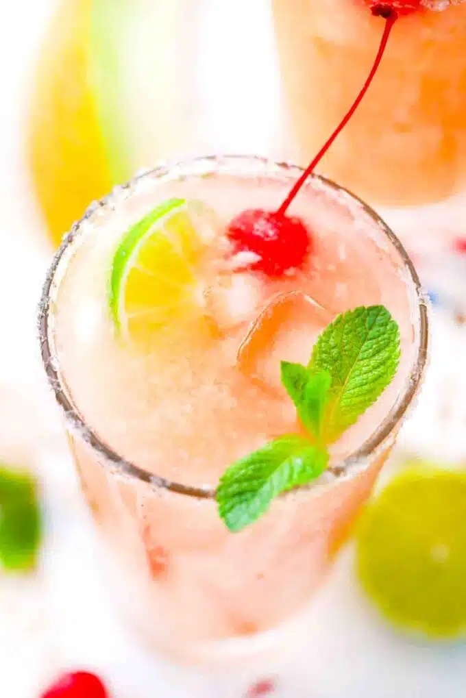 overhead shot of a glass with melon margarita topped with lime and a cherry