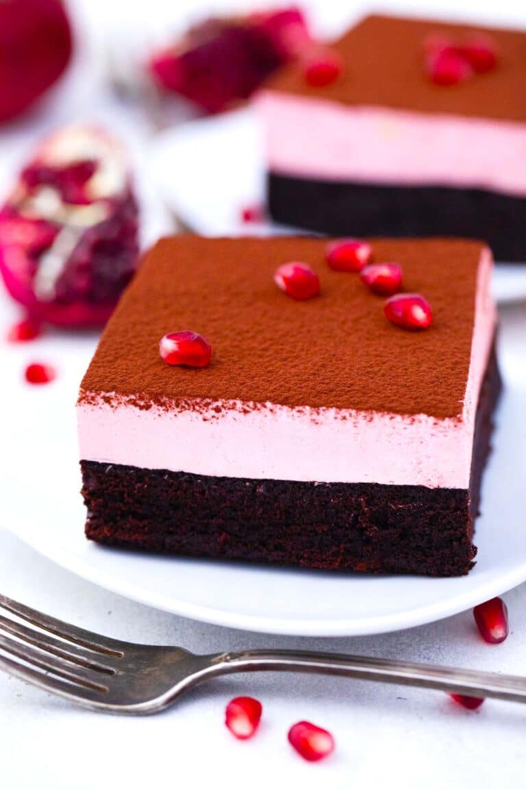 homemade pomegranate mousse brownies topped with cocoa powder and pomegranate arils