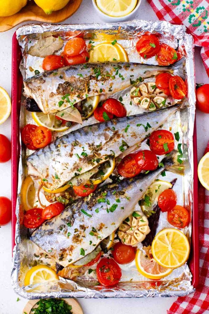 a baking dish with homemade roasted mackerel, tomatoes, herbs, and lemon