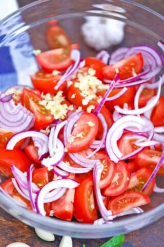 mixing tomatoes red onion and garlic in a bowl