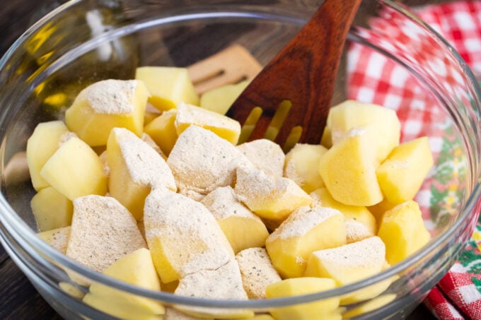 Mixing chopped potatoes with Ranch powder in a bowl.