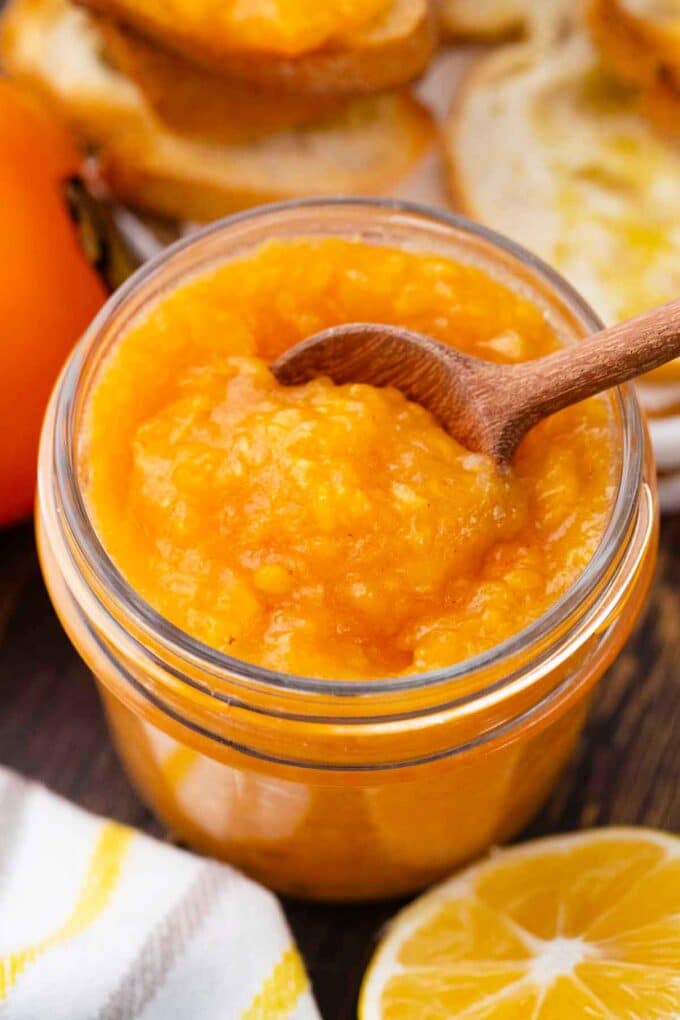 overhead shot of creamy persimmon jam with a serving spoon in it