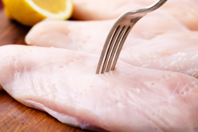 Poking chicken breast with a fork.