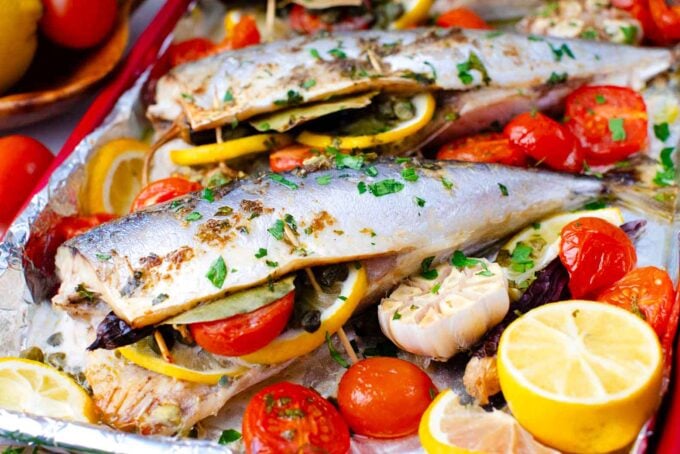 roasted Spanish mackerel on a baking dish with grape tomatoes and lemon