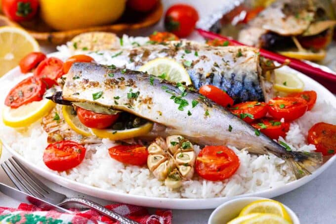 roasted Spanish mackerel with tomatoes and lemon on a plate of rice