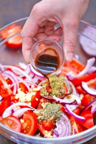 adding balsamic vinegar to a tomato salad