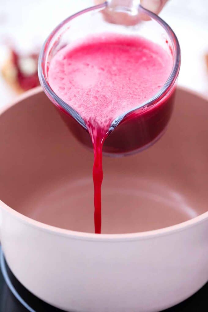 pouring pomegranate juice into a saucepan