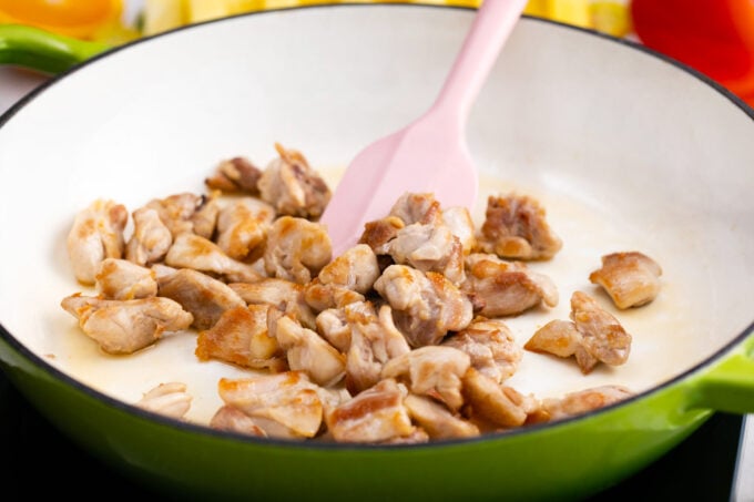 Searing chicken pieces in a cast iron pan.