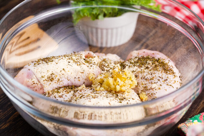 Season chicken thighs in a bowl.