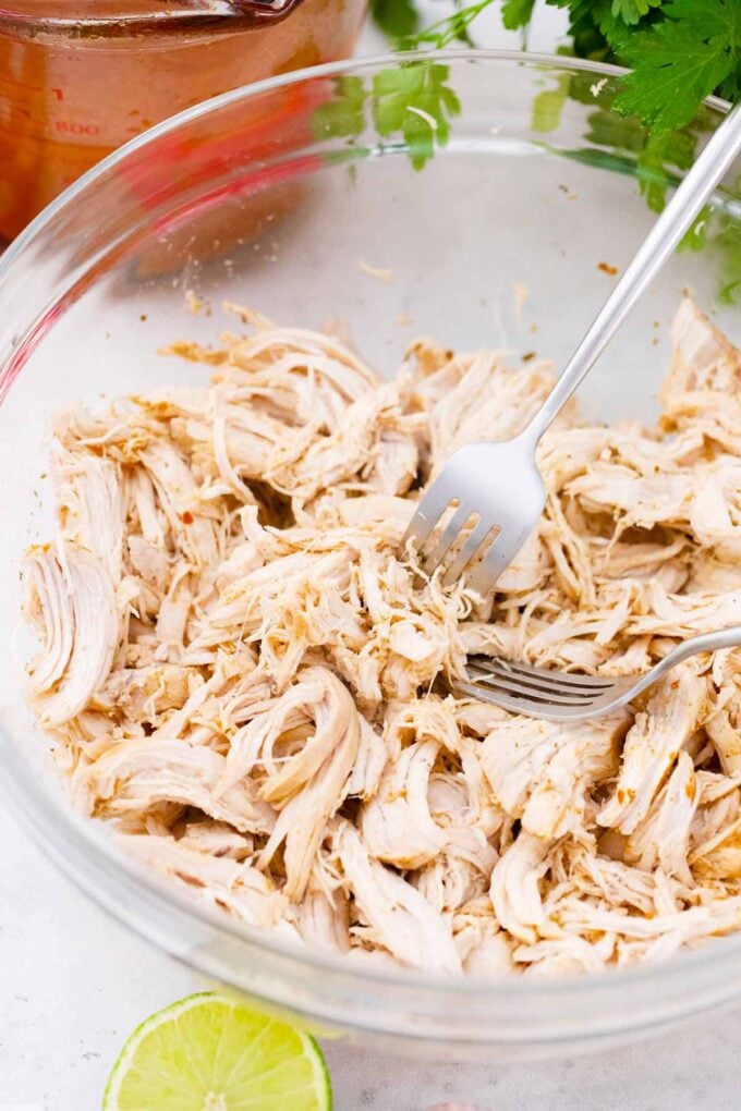 Shredding chicken breasts in a bowl.
