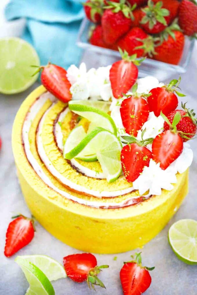 whole strawberry lime cake with vertical layers decorated with whipped cream and fresh strawberries