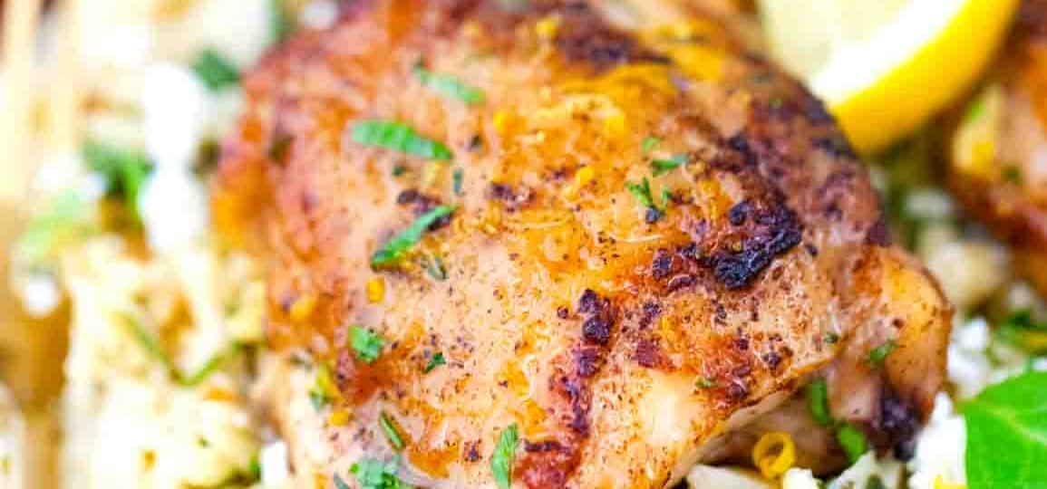 one pan chicken and orzo on a serving plate with lemon on the side