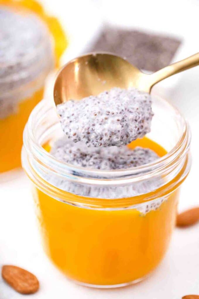 adding chia pudding layer to a mason jar with mango puree