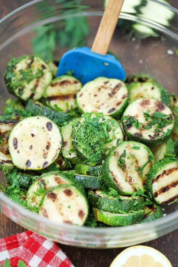 mixing grilled zucchini salad in a bowl