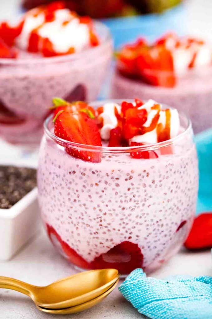 glasses filled with strawberry chia pudding topped with strawberries and whipped cream