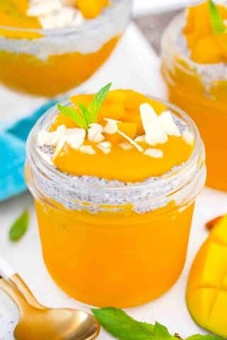 mango chia pudding in a small mason jar topped with mango almonds and mint