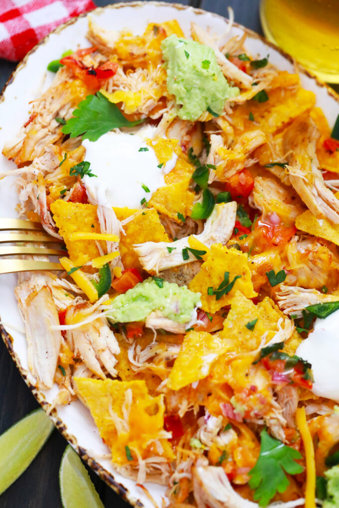 Homemade Instant Pot chicken nachos with shredded chicken, cheese, guacamole, and sour cream.