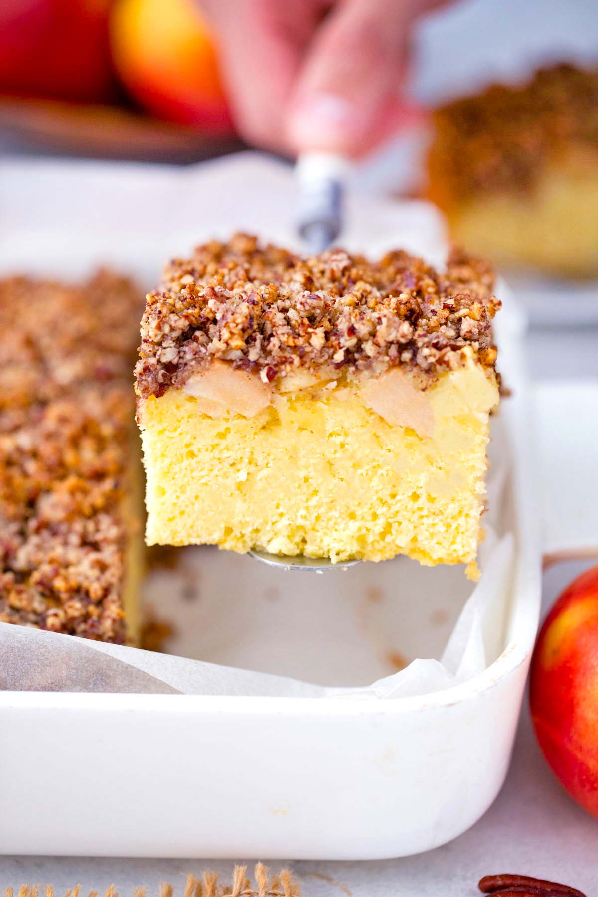 lifting a slice of apple sheet cake from the pan