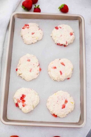 raw strawberry shortcakes on a baking sheet