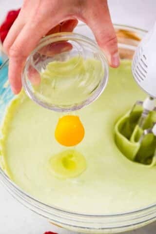 adding an egg to pistachio cheesecake batter