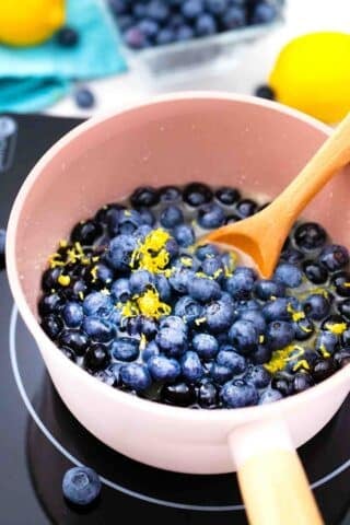 mixing blueberries and lemon zest in a saucepan on an electric stove