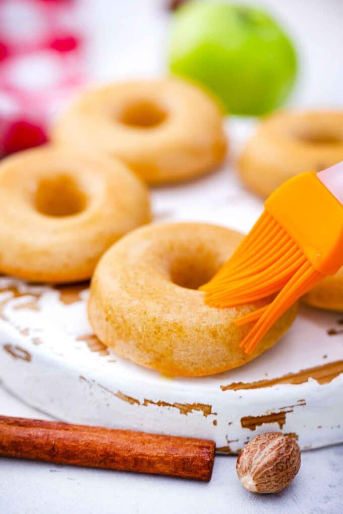 brushing apple cider donuts with cider glaze