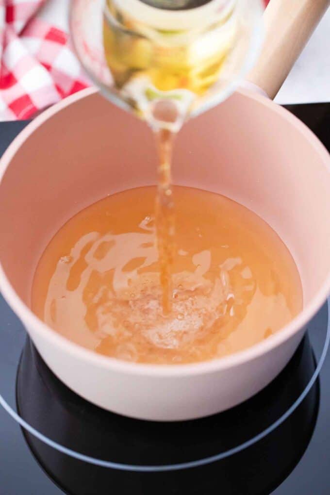 pouring apple cider in a small saucepan