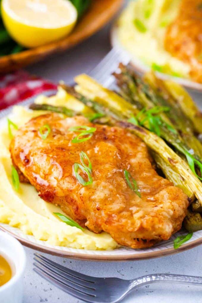 Crispy Cheesecake Factory honey truffle chicken served with mashed potatoes and roasted asparagus.