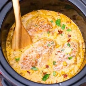 overhead shot of crockpot marry me chicken with a wooden spoon in it