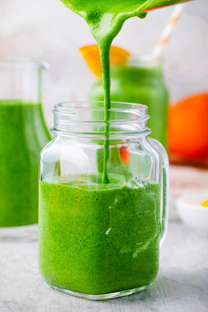 Pouring spinach smoothie into a mason jar.