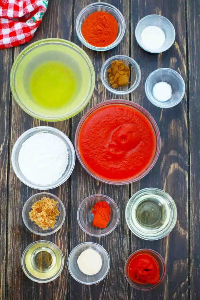 overhead shot of enchilada sauce ingredients in bowls on a wooden table