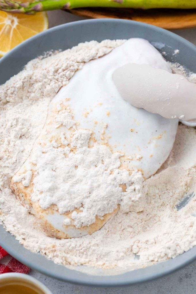 Tossing chicken breast in flour mixture.