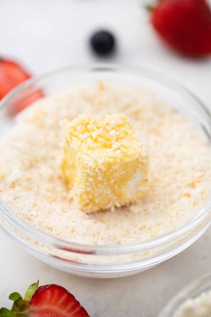 tossing brie cube in Panko break crumbs