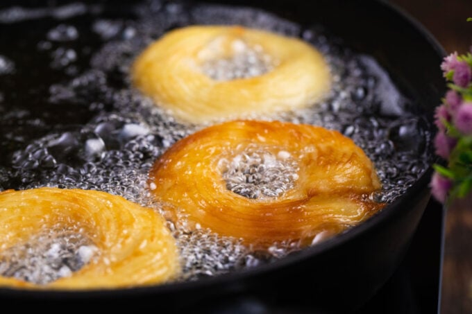 Frying French Crullers in hot oil.