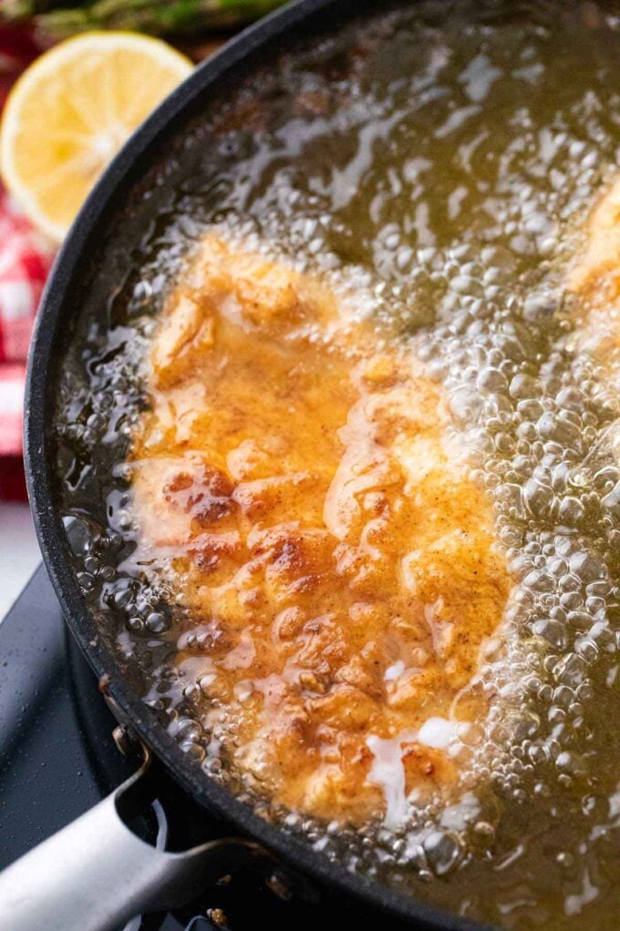 Frying breaded chicken breast in a cast iron with oil.