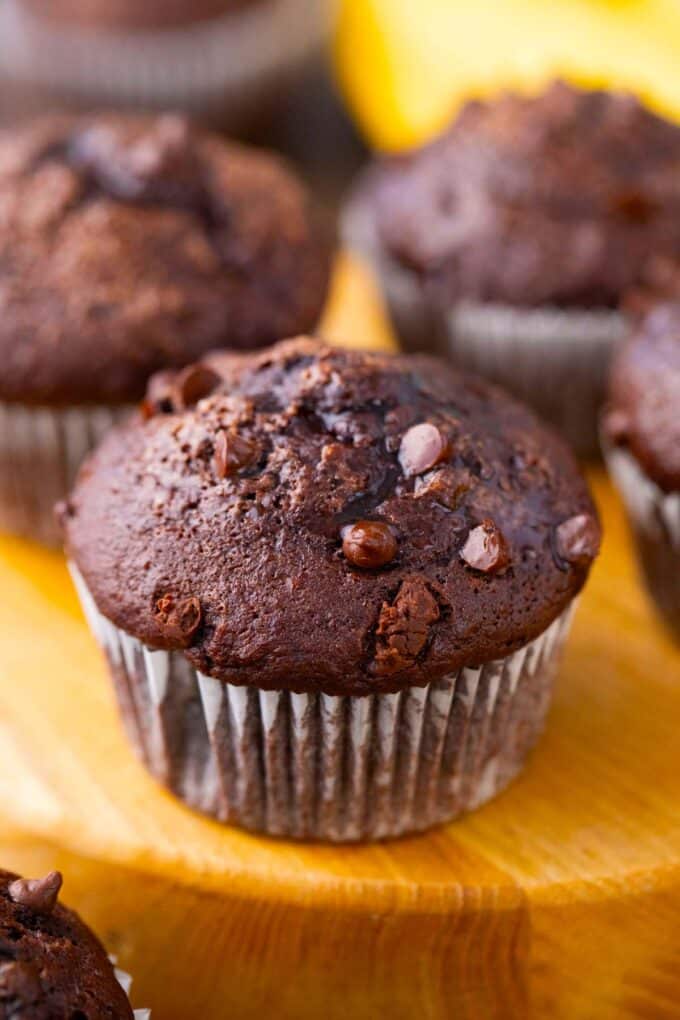 Fudgy chocolate banana muffins on a wood board.