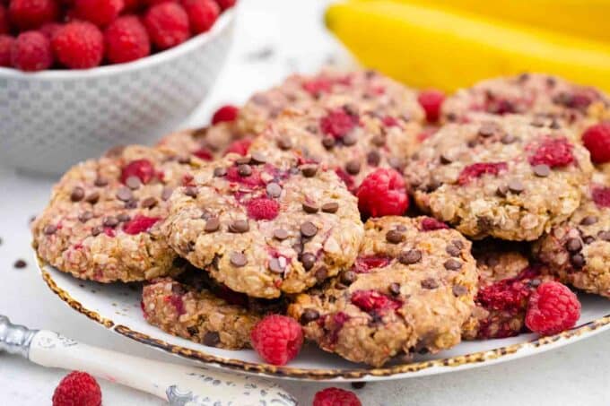 healthy raspberry cookies on a serving plate with a bowl of raspberries in the background