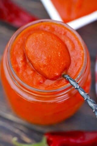 overhead shot of a jar of enchilada sauce with a spoon in it
