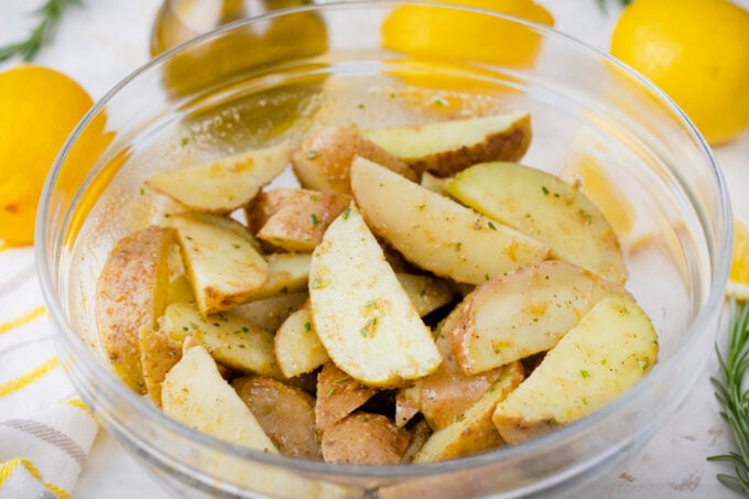 Mixing potato wedges with olive oil lemon marinade.