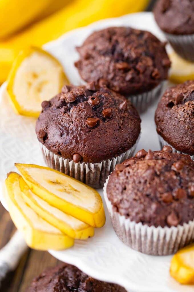 A cake platter with homemade chocolate banana bread muffins and banana slices.